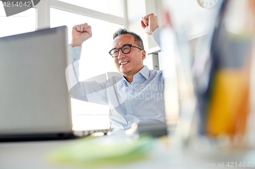 Image of happy businessman with laptop at office