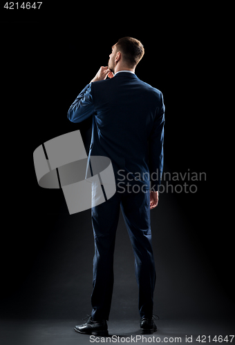 Image of businessman in suit over black