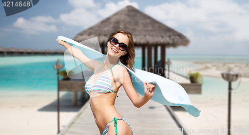 Image of woman in bikini and sunglasses with towel on beach