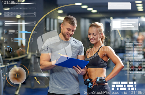 Image of smiling young woman with personal trainer in gym