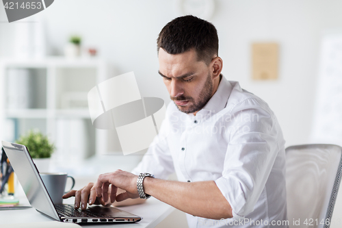 Image of businessman with laptop and wristwatch at office