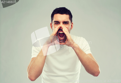 Image of angry shouting man in t-shirt over gray background