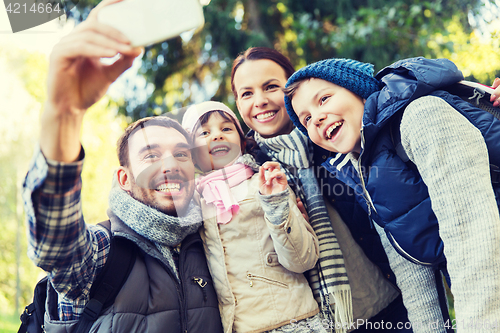 Image of family with backpacks taking selfie by smartphone