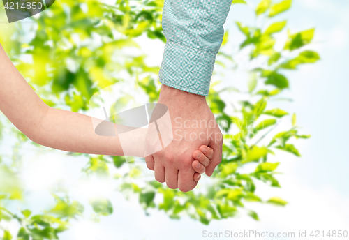 Image of father and child holding hands over green leaves