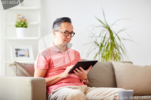 Image of man with tablet pc sitting on sofa at home
