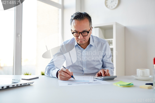 Image of businessman with calculator and papers at office