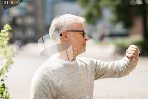 Image of senior man checking time on his wristwatch