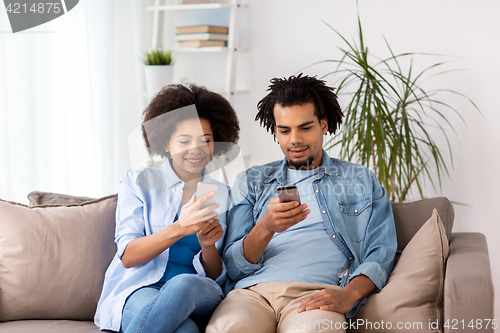 Image of happy couple with smartphones at home