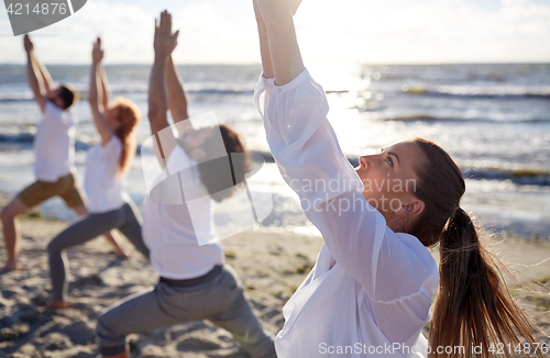 Image of group of people making yoga exercises on beach