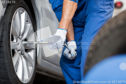 Image of mechanic with screwdriver changing car tire