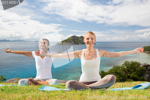 Image of happy couple making yoga exercises outdoors