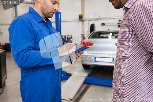 Image of auto mechanic with clipboard and man at car shop