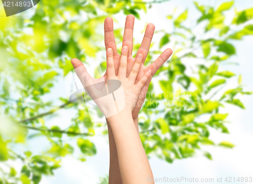 Image of father and child hands together over green leaves