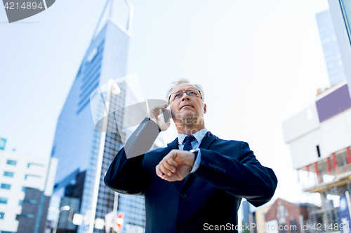 Image of senior businessman calling on smartphone in city