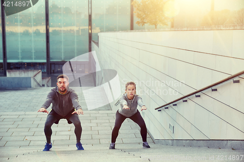 Image of couple doing squats on city street stairs