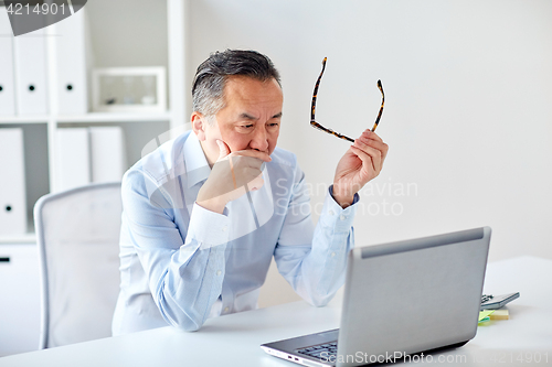 Image of businessman with eyeglasses and laptop at office
