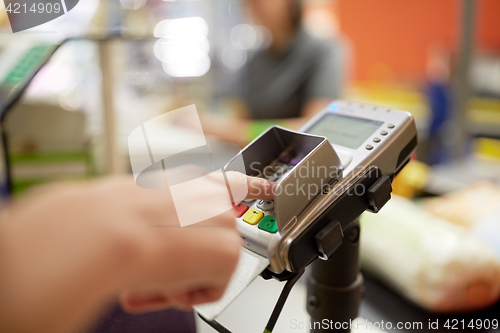 Image of woman entering pin code at store cash register