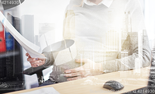 Image of pregnant businesswoman reading papers at office