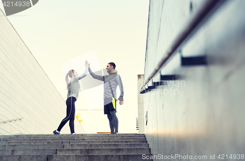 Image of smiling couple making high five on city street