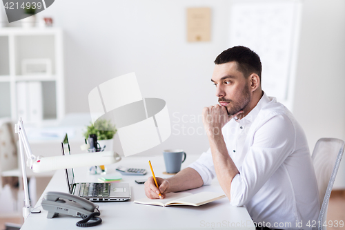 Image of businessman with laptop and notebook at office