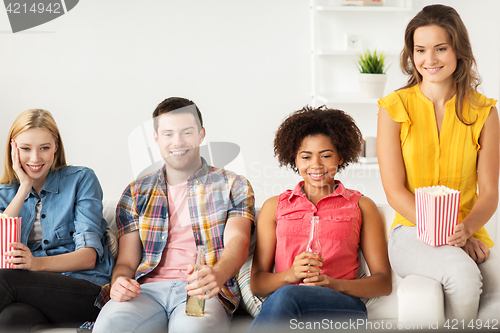 Image of happy friends with popcorn watching tv at home