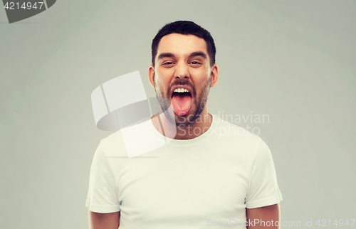 Image of man showing his tongue over gray background