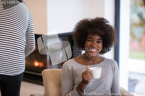 Image of black woman drinking coffee in front of fireplace