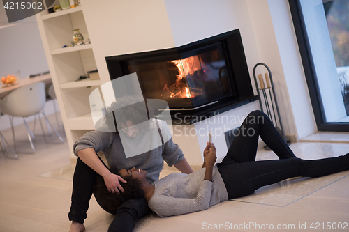 Image of multiethnic couple using tablet computer on the floor