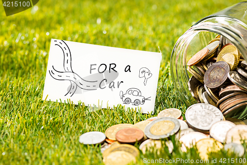 Image of The coins at glass jar for money on green grass