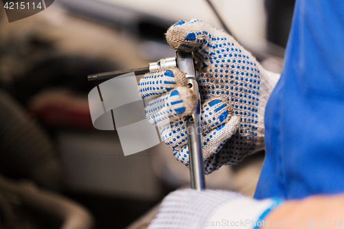 Image of mechanic man with wrench repairing car at workshop