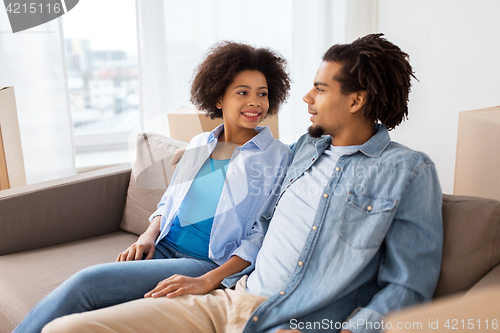 Image of happy couple sitting on sofa and talking at home