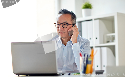 Image of businessman with laptop calling on smartphone