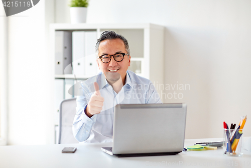 Image of businessman with laptop showing thumbs up