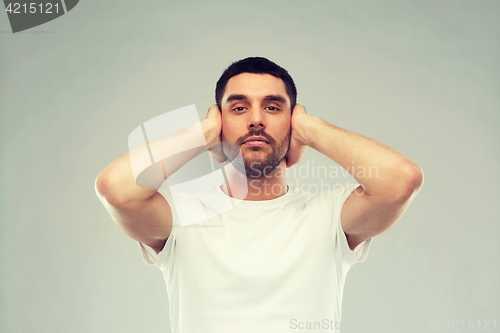 Image of latin man covering his ears with hand palms