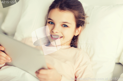 Image of happy girl lying in bed with tablet pc at home