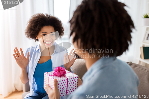 Image of happy couple with gift box at home