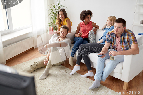 Image of friends with popcorn and beer watching tv at home