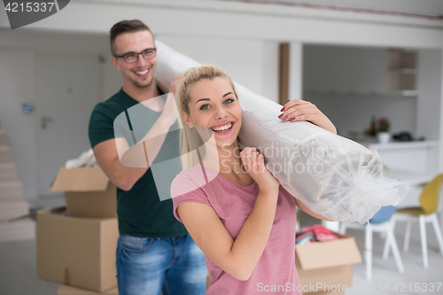 Image of couple carrying a carpet moving in to new home