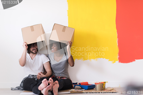 Image of young multiethnic couple playing with cardboard boxes