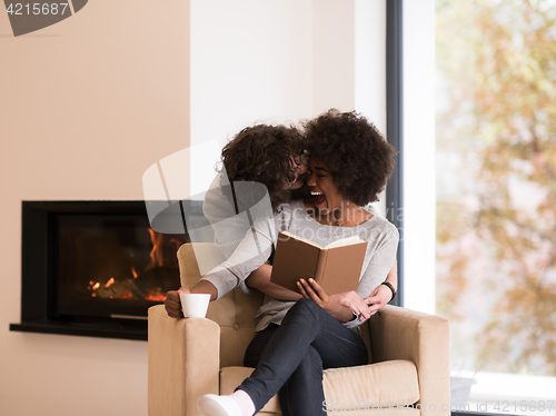 Image of multiethnic couple hugging in front of fireplace