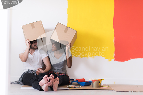 Image of young multiethnic couple playing with cardboard boxes