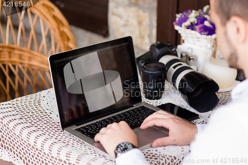 Image of happy young man working on laptop outdoors