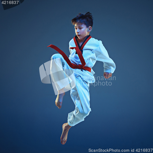 Image of Young boy training karate on blue background