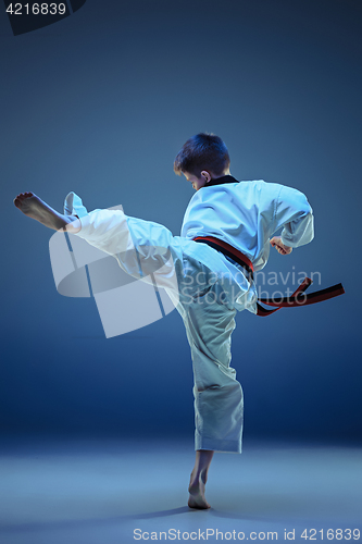 Image of Young boy training karate on blue background