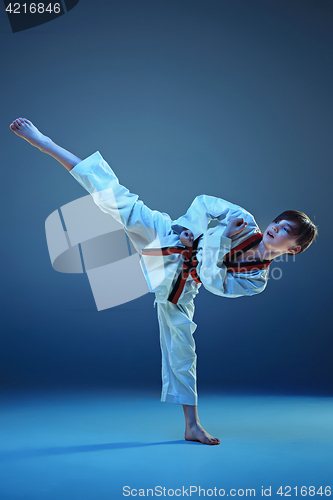 Image of Young boy training karate on blue background