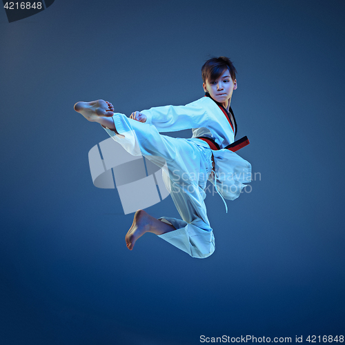 Image of Young boy training karate on blue background