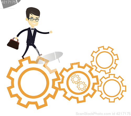 Image of Business man running on cogwheels.