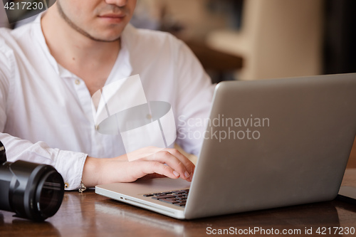 Image of photographer with the camera works on his laptop