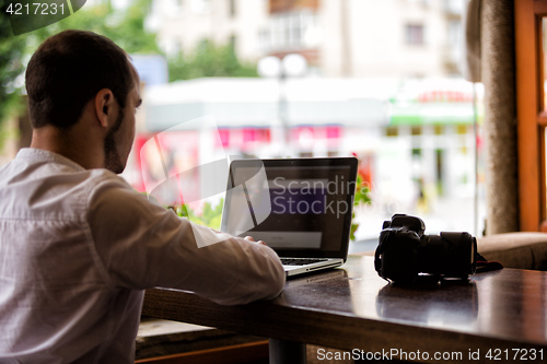 Image of photographer with the camera works on his laptop