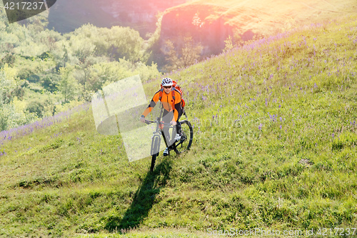 Image of Young man traveler riding on bicycle with red backpack